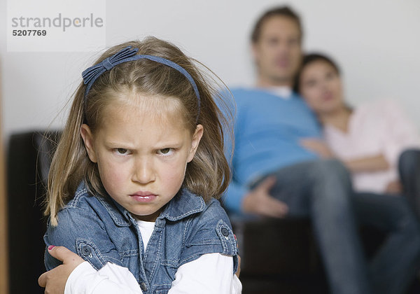 Kleines Mädchen  zornig  Eltern im Hintergrund