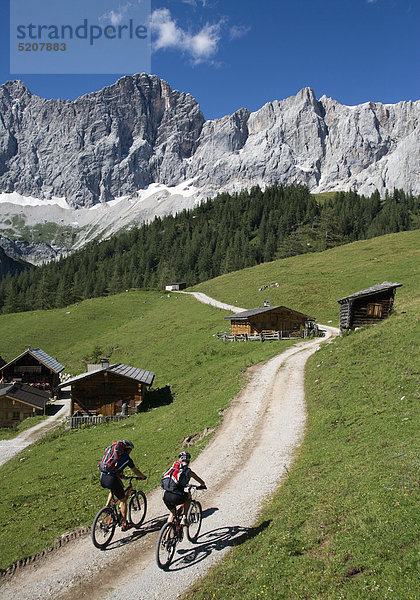 Mountainbiker auf Almweg in Berglandschaft