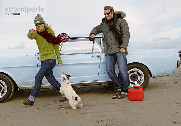 Paar im Herbst am Strand  mit Oldtimer und Hund