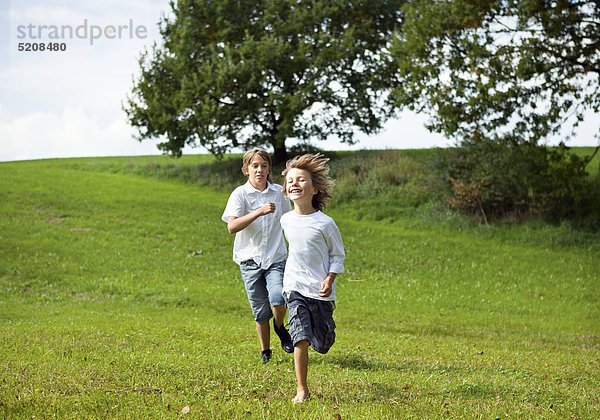 Zwei Jungen rennen über Wiese