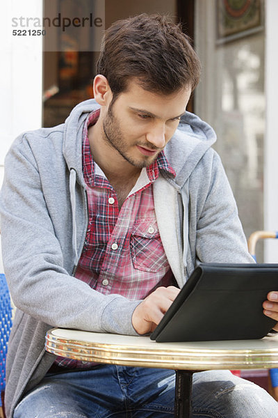 Mann  der auf einem Straßencafé mit einem digitalen Tablett sitzt  Paris  Ile-de-France  Frankreich
