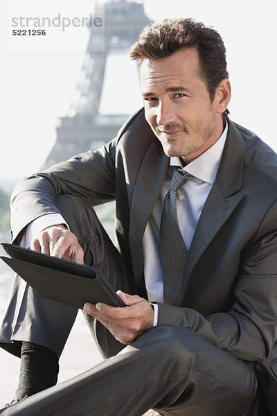 Geschäftsmann mit digitalem Tablett und Eiffelturm im Hintergrund  Paris  Ile-de-France  Frankreich
