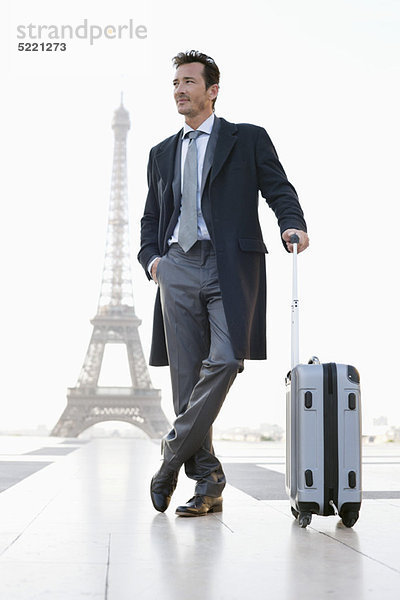 Geschäftsmann stehend mit Gepäck mit dem Eiffelturm im Hintergrund  Paris  Ile-de-France  Frankreich