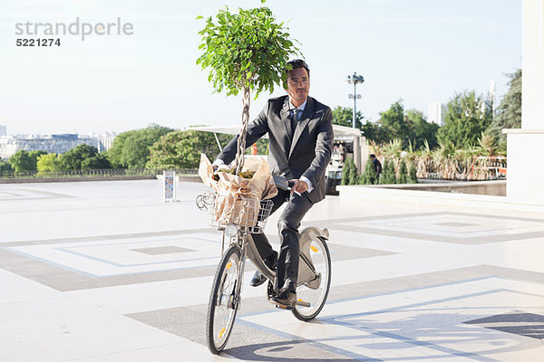 Geschäftsmann mit einer Pflanze auf einem Fahrrad  Eiffelturm  Paris  Ile-de-France  Frankreich