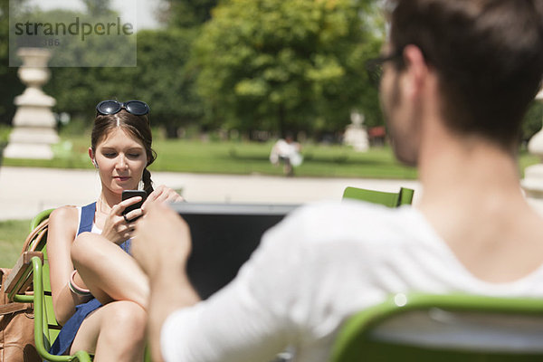 Frau SMS mit Handy  Jardin des Tuileries  Paris  Ile-de-France  Frankreich
