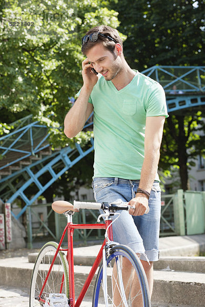 Mann  der mit dem Fahrrad geht und mit dem Handy spricht  Paris  Ile-de-France  Frankreich