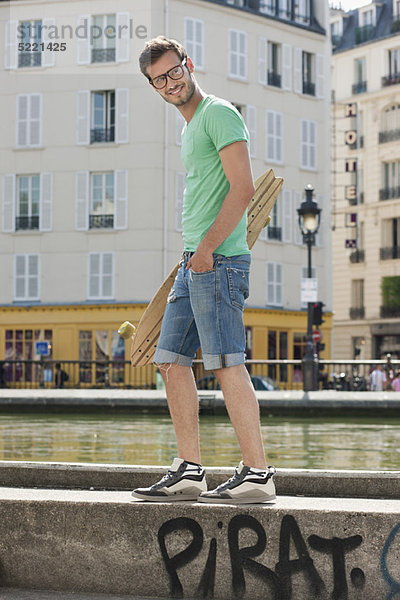 Mann  der ein Skateboard auf der Kante eines Kanals trägt  Canal St Martin  Paris  Ile-de-France  Frankreich