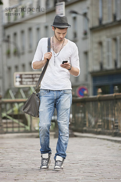 Mann unterwegs und SMS mit dem Handy  Paris  Ile-de-France  Frankreich