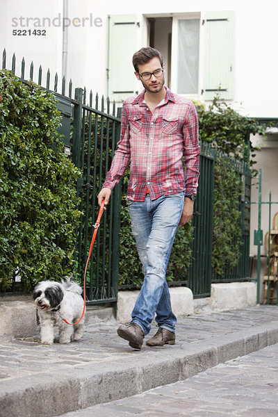 Mann  der einen Hund an der Leine hält  der auf einem Bürgersteig läuft  Paris  Ile-de-France  Frankreich