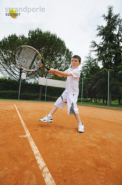 Junge trifft Tennis-Shot