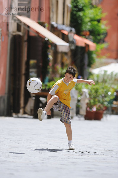 Junge spielen Fußball In Street