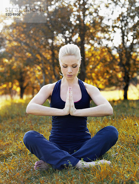 Eine Frau  die Yoga in der Natur praktiziert.