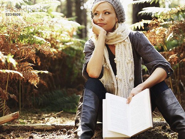 Eine Frau in Kontemplation  die ein Buch hält  im Freien