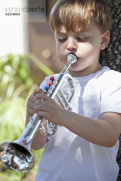 Ein Junge spielt eine Spielzeug-Trompete.