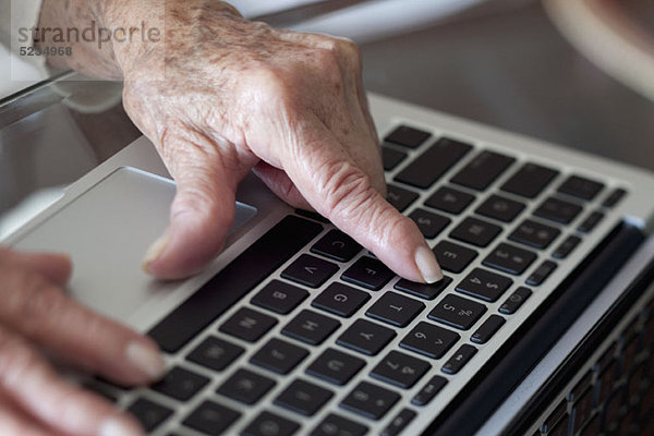 Detail einer älteren Frau  die einen Laptop benutzt.