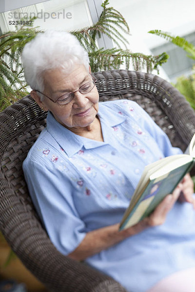 Eine ältere Frau liest in einem Sessel.