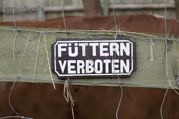 A FEEDING FORBIDDEN Schild in deutscher Sprache am Zaun hängend  Nahaufnahme