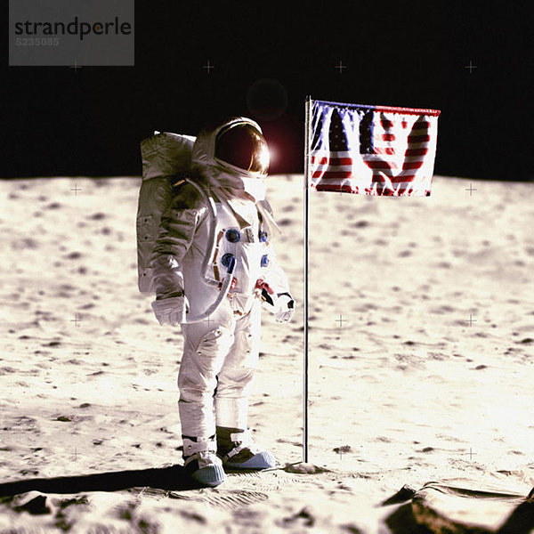 Ein Astronaut neben einer amerikanischen Flagge auf dem Mond