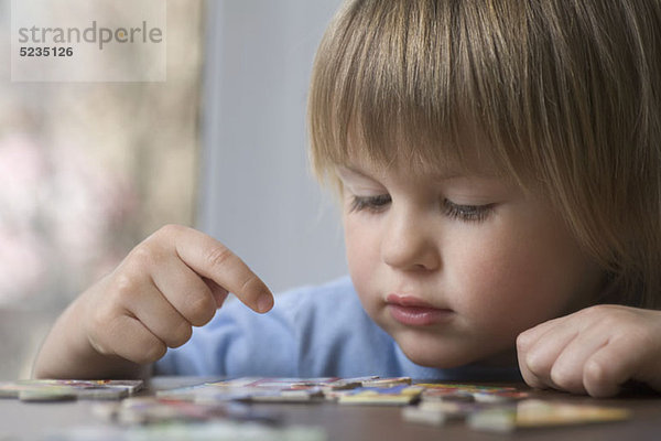 Ein kleiner Junge  der ein Puzzle zusammenstellt.