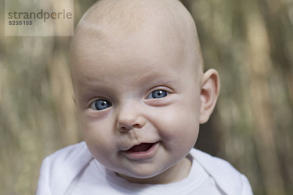 Ein Baby mit einem lustigen Gesichtsausdruck  das in die Kamera schaut.