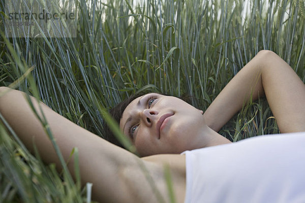 Eine Frau  die im Gras liegt und träumt.