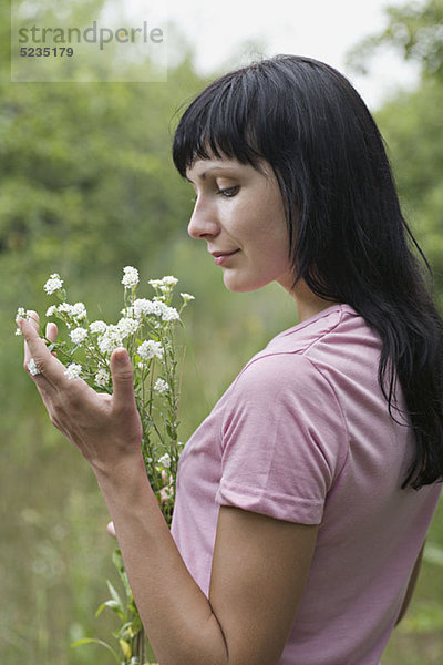 Eine Frau  die einen Haufen Wildblumen bewundert.