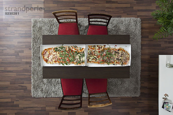 Zwei große Pizzen nebeneinander auf einer Tischlänge  Draufsicht