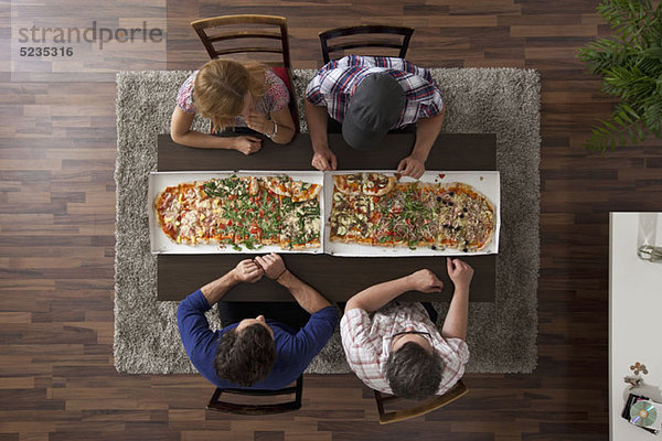 Vier Freunde machen sich bereit  zwei große Pizzen zu essen  Blick nach oben