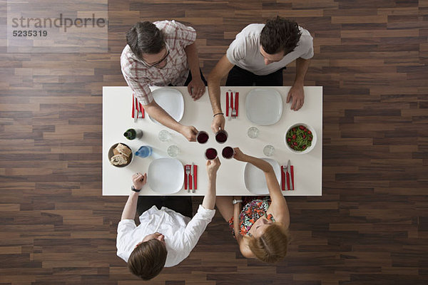 Vier Freunde stoßen bei einer Dinnerparty an  Blick über den Tellerrand
