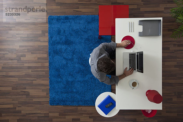 Ein Geschäftsmann  der an seinem Schreibtisch in seinem Home-Office arbeitet  Blick über den Kopf