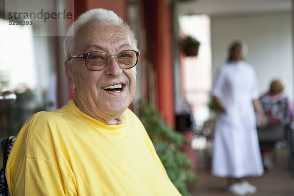 Ein fröhlicher älterer Mann entspannt sich in einem Pflegeheim