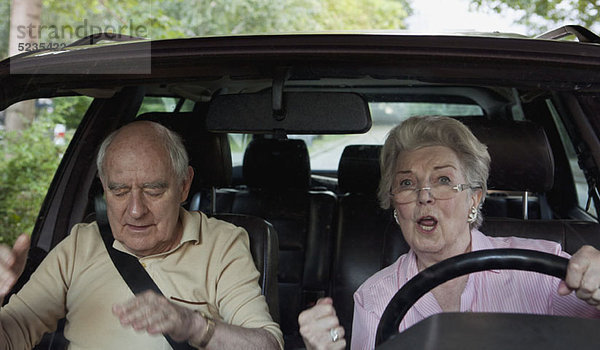 Frau  die das Fahren lernt  wird aufgeregt  während der Mann auf dem Beifahrersitz zur Ruhe kommt.