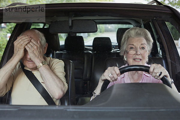 Frau hat Probleme beim Fahren  während der Mann auf dem Beifahrersitz verzweifelt ist.