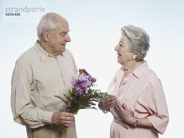 Senior Mann schenkt Seniorin Blumen