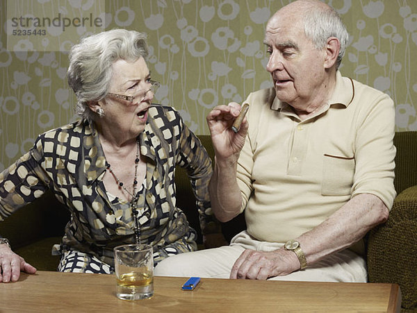 Senior Frau sieht schockiert aus  als der Senior Mann Zigarre raucht.