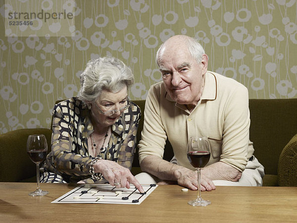 Senior Mann Grimassen als Senior Frau erwägt eine Bewegung spielen Mühle