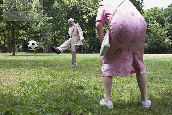 Seniorenpaar spielt Fußball im Park