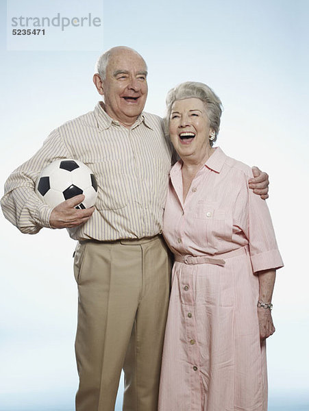 Senior Paar lacht als Mann hält Fußball