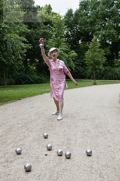 Seniorin spielt Boules im Park