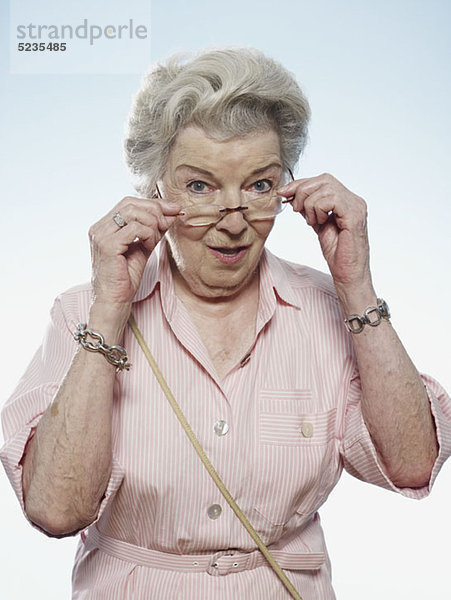 Profil der älteren Frau  die über ihre Brille blickt