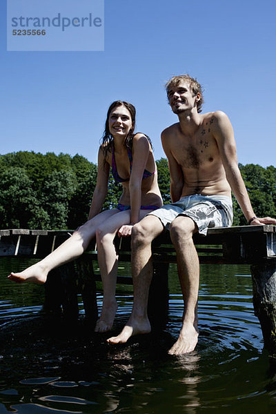 Paar nebeneinander auf Steg tauchende Füße im See