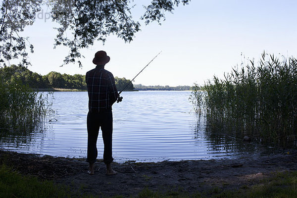 Mann beim Angeln am See