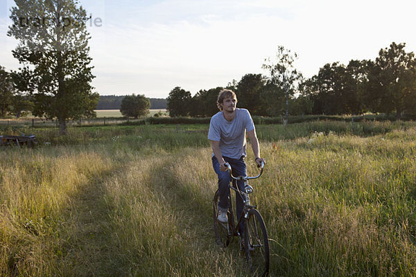 Guy fährt mit dem Fahrrad durch ein abgelegenes Feld.