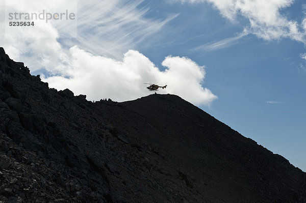 Der Wetterstein  Tirol  Österreich  Helikopter in der Ferne über einem Silhouettenberg