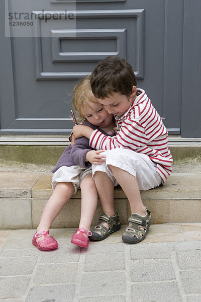 Junge Geschwister umarmen sich im Freien