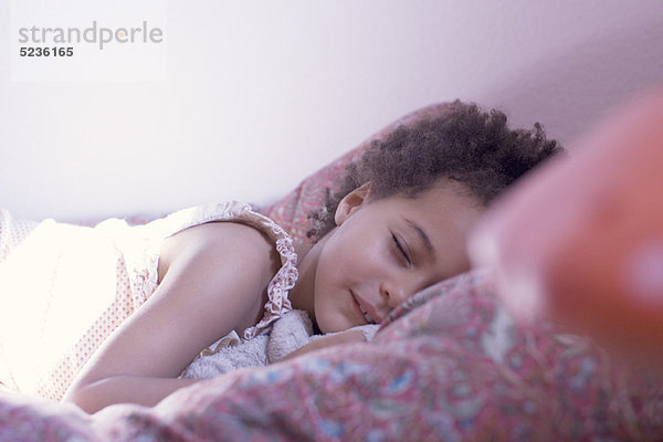 Kleines Mädchen auf dem Bett liegend mit geschlossenen Augen