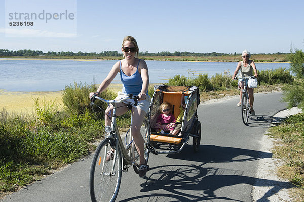 Mehrgenerationen-Familie genießt Fahrradfahren  Kinder sitzen im Fahrradanhänger