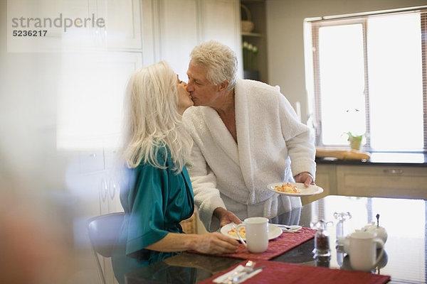 Älteres Paar im Bademantel beim Frühstück
