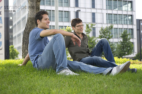 Männer sitzen im Gras in der Stadt