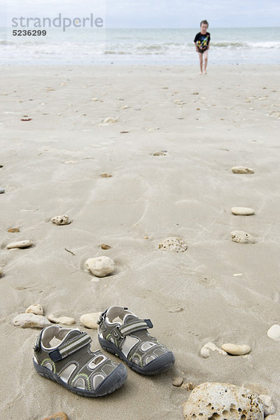 Junge am Strand  Fokus auf Sandalen im Vordergrund